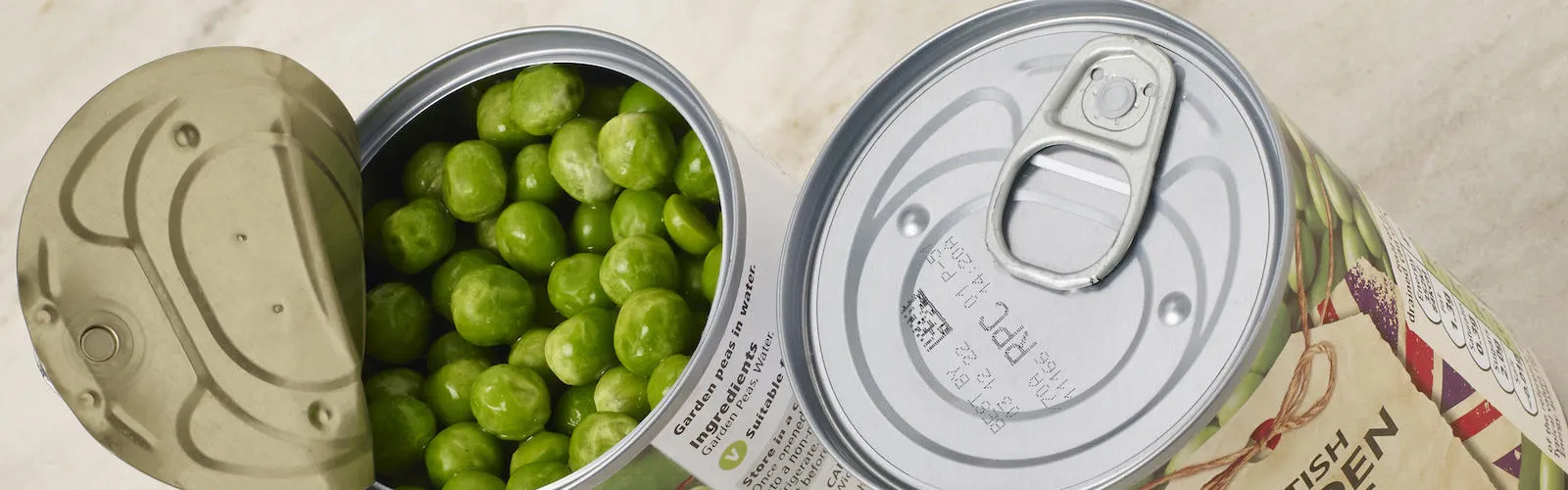 canned peas. One with the lid peeled open and the other closed showing codes