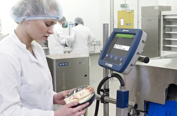employee inspecting food sleeve in front of domino touch panel