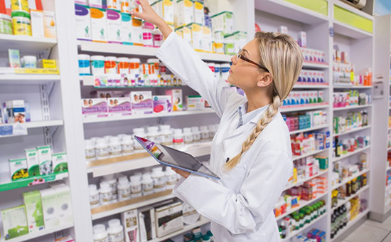Pharmacist inspects shelf of medcines