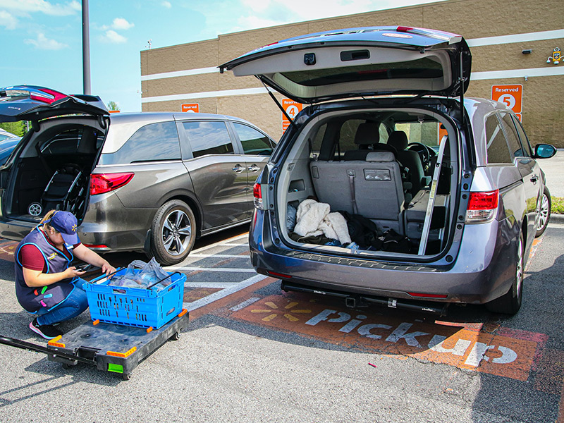 Person loading shopping into the back of an open car