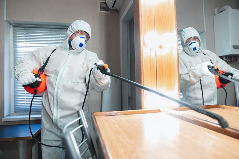 Person wearing full white personal protective equipment, including face mask