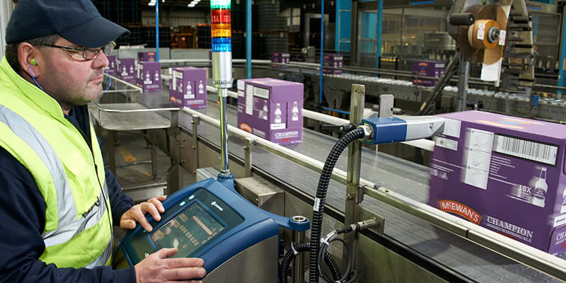 Wells & Young employee using Domino printer screen and checking production line 