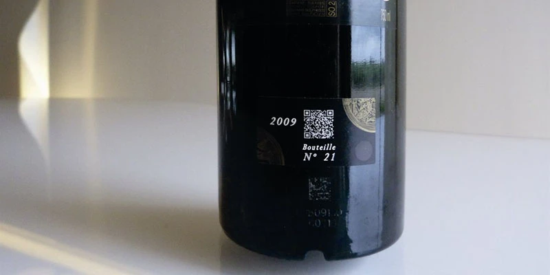Glass bottle of red wine with white QR code printed on the side